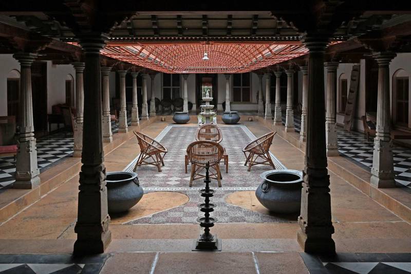 Chettinad mansion courtyard with carved wooden pillars and a lamp